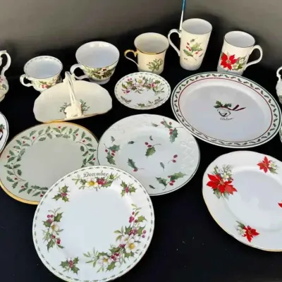 Sale Photo Thumbnail #70: Assorted Christmas-themed porcelain tableware, featuring various holly, poinsettia, and holiday motifs on plates, mugs, cups, and serving pieces.