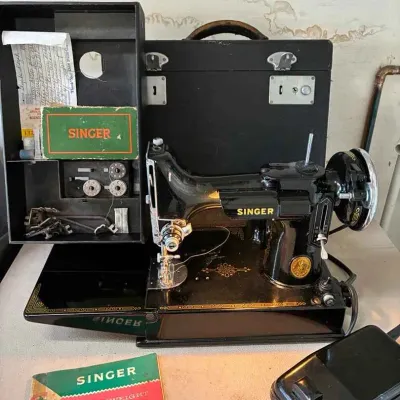 Sale Photo Thumbnail #6: Vintage Singer Featherweight 221 sewing machine with its original black carrying case, foot pedal, manual, and accessory tray.