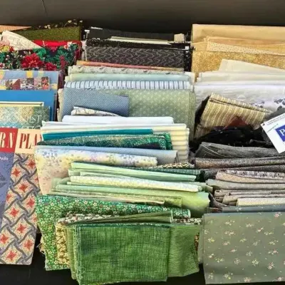 Sale Photo Thumbnail #33: Large collection of quilting fabric quarters and scraps in various colors and patterns, accompanied by a quilting pattern book.