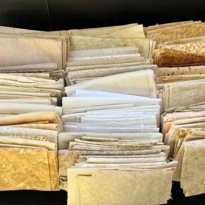 Sale Photo Thumbnail #31: Large assortment of folded quilting fabric remnants in neutral, cream, and gold tones, featuring various subtle patterns and textures.