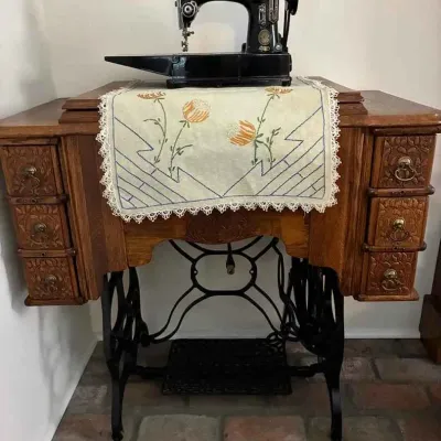 Sale Photo Thumbnail #144: Vintage Singer sewing machine mounted on an ornate oak treadle cabinet with carved drawers and a cast iron base.