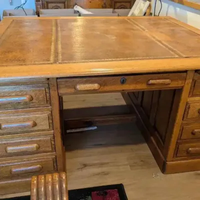 Sale Photo Thumbnail #197: Large oak double pedestal desk featuring a three-panel leather top with gold-tooled borders and wooden drawer pulls.