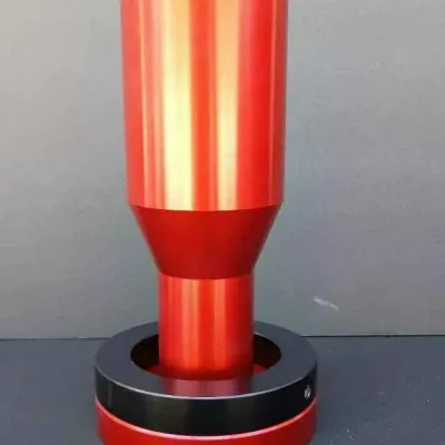 Sale Photo Thumbnail #143: Red anodized aluminum tool or component, possibly a bearing press adapter or custom mandrel, resting on a black and red circular base.