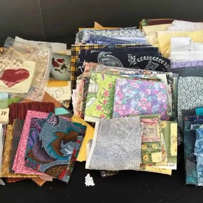 Sale Photo Thumbnail #66: Large assortment of quilting fabric remnants and craft kits, including a Hawaiian Quilt Pillow Kit and various patterned fabric quarters.