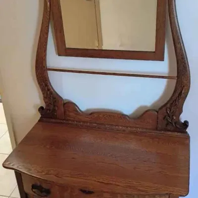 Sale Photo Thumbnail #168: Antique oak washstand featuring a swivel mirror with elegant curved supports, a single drawer with ornate metal pulls, and a lower two-door cabinet.