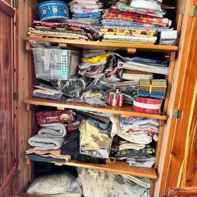 Sale Photo Thumbnail #172: A wooden armoire filled with a large collection of sewing fabrics, textiles, and crafting supplies.