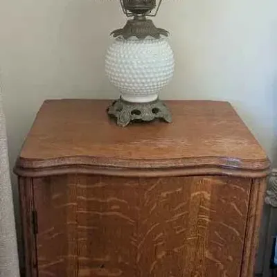 Sale Photo Thumbnail #80: Vintage white hobnail glass hurricane lamp with brass-toned metal base and trim, displayed on an antique tiger oak cabinet.