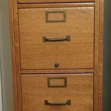 Sale Photo Thumbnail #99: Vintage four-drawer oak filing cabinet featuring brass hardware, label holders, and a top lock mechanism.