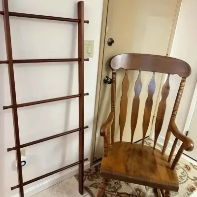 Sale Photo Thumbnail #178: Wooden blanket ladder in a dark finish alongside a classic wooden rocking chair with a spindle back.