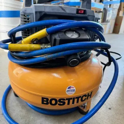 Sale Photo Thumbnail #137: Bostitch pancake air compressor, model BTFP02012, featuring a yellow tank and wrapped with a blue air hose.