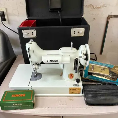 Sale Photo Thumbnail #175: Vintage white Singer sewing machine model 328K with its black carrying case, foot pedal, and original boxed attachments.