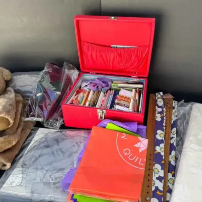 Sale Photo Thumbnail #74: Assorted crafting and sewing supplies, featuring a red vintage sewing box filled with notions, a plush teddy bear, patterns, and colorful fabrics.