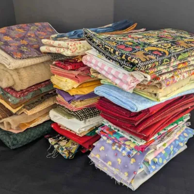 Sale Photo Thumbnail #30: Large assortment of folded fabric remnants and quilting squares in various colors, patterns, and textures.