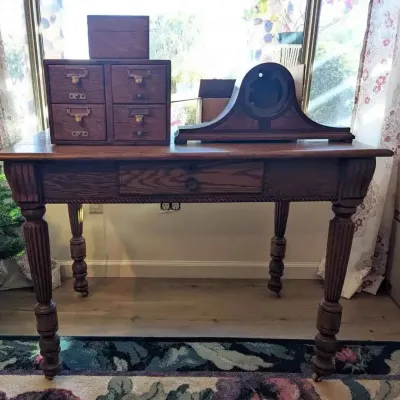 Sale Photo Thumbnail #196: Antique oak library table with a single drawer and turned legs, topped with a small four-drawer card catalog cabinet and an empty wooden mantel clock case.