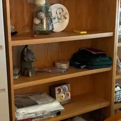 Sale Photo Thumbnail #192: Tall oak bookcase featuring adjustable shelves and a crown molding top, shown holding various decorative items and storage bins.