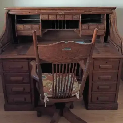 Sale Photo Thumbnail #147: Antique oak rolltop desk featuring a detailed interior organizer with small drawers and cubbies, paired with a matching wooden swivel desk chair.