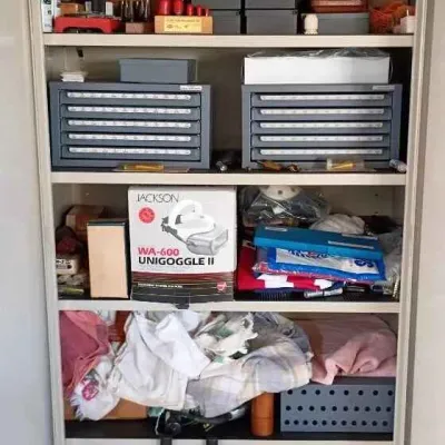 Sale Photo Thumbnail #42: Tall metal storage cabinet on wheels, filled with various workshop items, tools, safety gear, and linens.