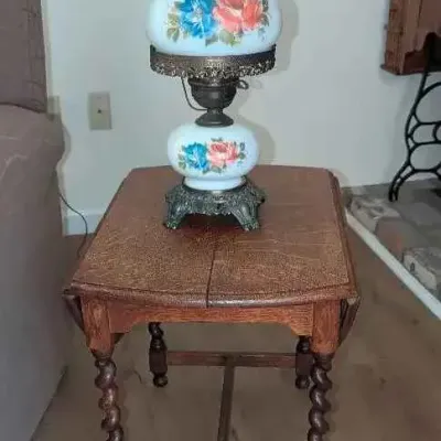 Sale Photo Thumbnail #12: Vintage hurricane-style table lamp with floral-painted milk glass globes, resting on a wooden drop-leaf side table featuring barley twist legs.