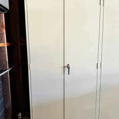 Sale Photo Thumbnail #122: Tennsco beige metal storage cabinet featuring a two-door design with a central locking handle, set on casters for easy mobility.