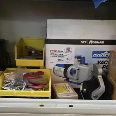 Sale Photo Thumbnail #134: Guardian 20-ton bottle jack, SPX Robinair CoolTech vacuum pump in its original box, and various hardware including Campbell Chain single jack chains, stored on a shelf.