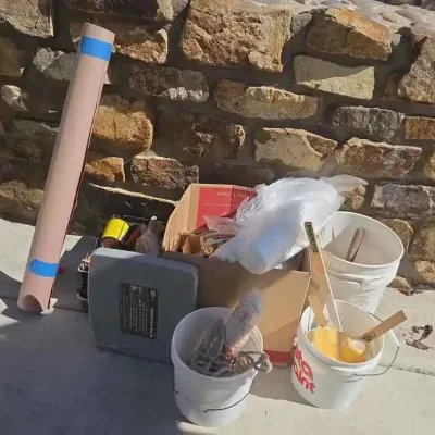 Sale Photo Thumbnail #83: Assorted painting and home improvement supplies, including plastic buckets, paint stirrers, a cardboard box of materials, and a roll of paper.