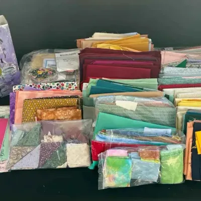Sale Photo Thumbnail #55: Large collection of quilting and sewing supplies, including various fabric remnants, fat quarters, and sewing patterns.