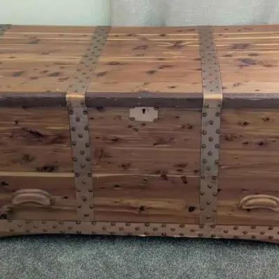 Sale Photo Thumbnail #3: Vintage cedar hope chest featuring copper-toned metal strapping with decorative rivets and a lower drawer with wooden pulls.