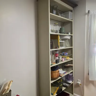 Sale Photo Thumbnail #134: Tall beige metal shelving unit filled with various household items, kitchenware, and storage containers.