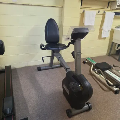 Sale Photo Thumbnail #197: Schwinn recumbent exercise bike with adjustable seat and digital display console, shown alongside other vintage home gym equipment.