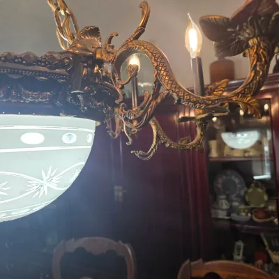Sale Photo Thumbnail #3: Ornate Victorian-style brass chandelier featuring a frosted glass dome with cut starburst patterns and decorative scrollwork arms.