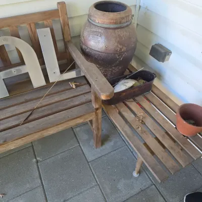 Sale Photo Thumbnail #218: Rustic wooden outdoor bench and matching slatted side table, featuring a large vintage brown glazed ceramic urn and assorted garden pots.