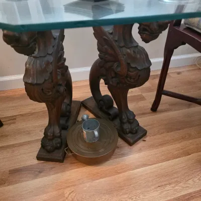 Sale Photo Thumbnail #57: Ornate carved wood trestle table featuring winged griffin supports and a thick, beveled glass top.