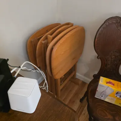 Sale Photo Thumbnail #84: Set of four vintage wooden folding TV tray tables with a matching storage stand, shown alongside an ornate carved wooden chair.