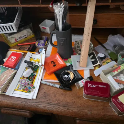 Sale Photo Thumbnail #104: Assortment of vintage desk accessories and collectibles, including Playboy memorabilia, playing cards, small tins, and office supplies.