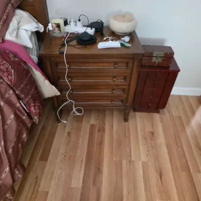 Sale Photo Thumbnail #117: Traditional wood nightstand with three drawers and brass pulls, shown alongside a smaller wooden jewelry chest on a laminate floor.
