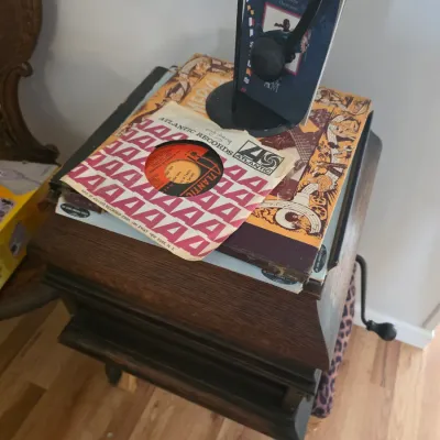 Sale Photo Thumbnail #74: Vintage Atlantic Records 45 RPM vinyl record in its original paper sleeve, resting on a stack of books atop a wooden side table.