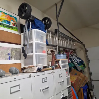 Sale Photo Thumbnail #176: Assorted garage storage items, including a white metal filing cabinet, a three-drawer plastic storage cart, a folding utility wagon, and an aluminum extension ladder.
