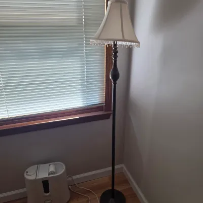Sale Photo Thumbnail #96: Traditional dark metal floor lamp featuring a turned wood-style accent on the post and a cream fabric bell shade with beaded fringe.