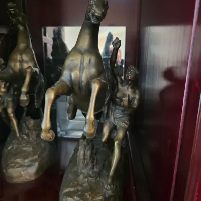 Sale Photo Thumbnail #13: Pair of bronze-finished Marly horse statues, depicting a rearing horse and groom on a rocky base, displayed in a wooden cabinet.