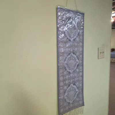 Sale Photo Thumbnail #209: Woven tapestry wall hanging featuring three ornate medallions in shades of grey and silver, complete with bottom fringe and a protective plastic cover.