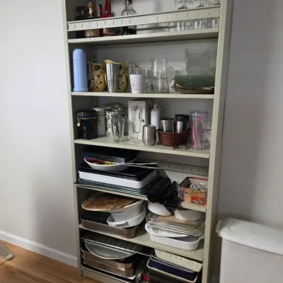 Sale Photo Thumbnail #147: Tall metal shelving unit filled with kitchenware, including glassware, baking dishes, and bar accessories.