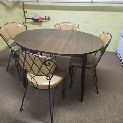 Sale Photo Thumbnail #200: Mid-century dinette set featuring an oval laminate wood-grain table and four wrought iron chairs with tan vinyl cushions.