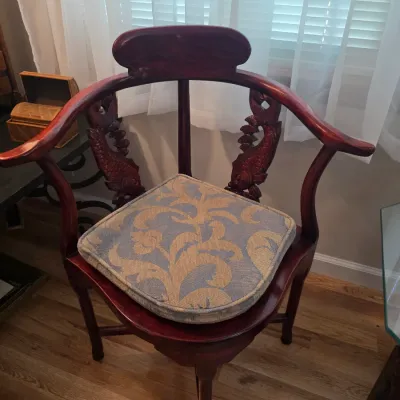 Sale Photo Thumbnail #56: Vintage Asian-style corner chair in a dark reddish-brown finish, featuring carved fish splats and a blue and gold patterned seat cushion.