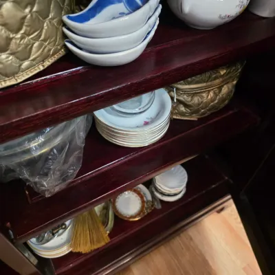 Sale Photo Thumbnail #28: Assorted vintage porcelain dishes, saucers, and small bowls displayed on dark wood cabinet shelves.