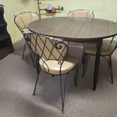 Sale Photo Thumbnail #201: Mid-century dinette set featuring a round laminate wood-grain table and four wrought iron chairs with tan vinyl cushions.