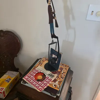 Sale Photo Thumbnail #73: Vintage metal balancing toy depicting a soldier with a rifle, displayed on top of vintage vinyl records and a wooden cabinet.