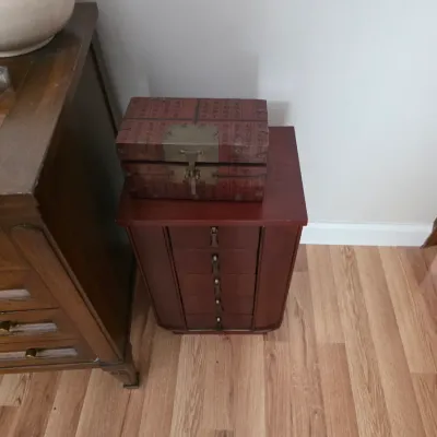 Sale Photo Thumbnail #118: Small cherry-finished jewelry armoire with five drawers, topped with an Asian-style decorative wooden box featuring brass hardware.