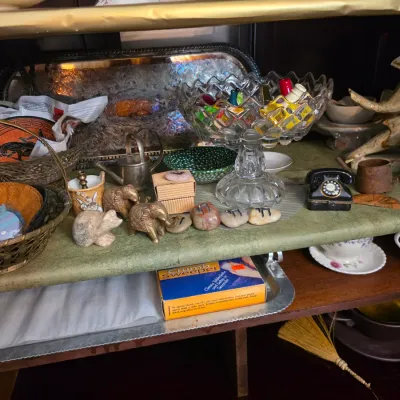 Sale Photo Thumbnail #25: Assorted vintage collectibles and home decor items, including a cut-glass pedestal bowl, brass elephant figurines, woven baskets, and a novelty telephone-shaped container.