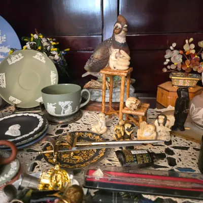 Sale Photo Thumbnail #36: Collection of vintage collectibles including Wedgwood jasperware in blue, green, and black, small carved figurines, a ceramic quail statue, and decorative Asian-style pottery.