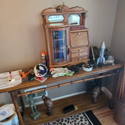 Sale Photo Thumbnail #177: Faux-bamboo wooden console table featuring a miniature oak secretary desk with a curved glass display cabinet, alongside various decorative sculptures and collectibles.